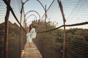 a woman in a white dress walking on a suspension bridge at Azulik in Tulum