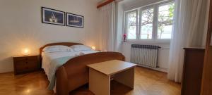 a bedroom with a bed with a table and a window at Apartments Anamarija in Opatija