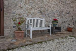 un banc blanc assis à côté d'un mur en pierre dans l'établissement Podere del Papa, à Viceno