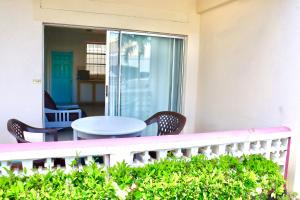 a patio with a table and chairs on a balcony at Melrose Beach Apartments Inc in Bridgetown