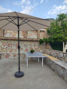 a white table with an umbrella in front of a stone wall at Casa di Athi in Sami