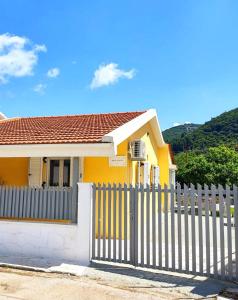 een geel huis met een hek ervoor bij Casa di Athi in Sami