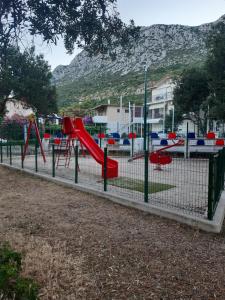 a playground with a red slide in a park at Pansion Ana in Podaca