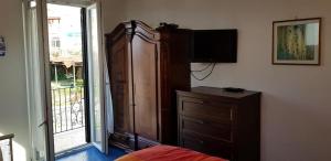 een slaapkamer met een grote houten kast en een televisie bij Casetta Miluna in Ischia