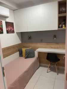a small bedroom with a bed and a desk at Branco Haus - Pé na Areia do Caribessa in João Pessoa