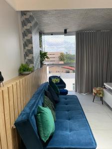 a blue couch with green pillows in a living room at Branco Haus - Pé na Areia do Caribessa in João Pessoa