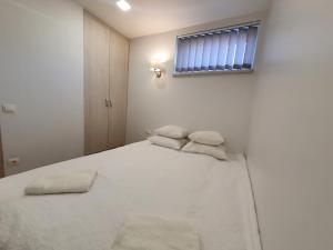 a bedroom with a white bed with a window at S&S Apartments in Palanga