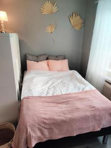 a bedroom with a bed with a pink blanket on it at Viihtyisä yksiö Porissa in Pori
