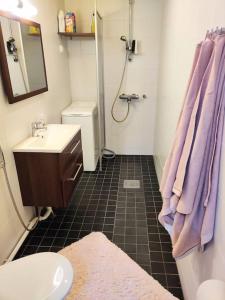 uma casa de banho com um lavatório e um chuveiro com toalhas roxas em Viihtyisä yksiö Porissa em Pori