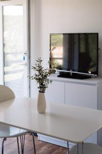 a white table with a tv and a vase on it at Nature House with a wooden porch - Pasika, house Tonka in Pučišća