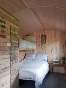 uma cama num quarto com paredes de madeira em orchard meadow shepherd huts leek-buxton-ashbourne em Upper Elkstone