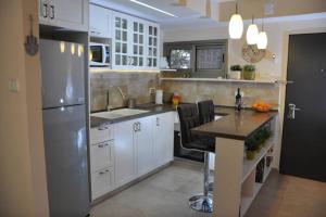 a kitchen with white cabinets and a stainless steel refrigerator at Mory's Place - Luxurious Holiday Apartment in Arad