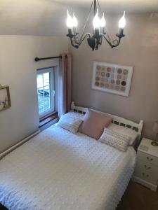 1 dormitorio con 1 cama blanca y ventana en Cosy Rustic 3 bed cottage, great train links en Bebington