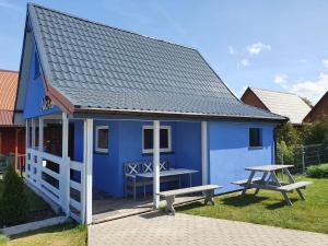 a blue house with a picnic table and a bench at Domek letniskowy in Łukęcin