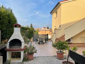 eine Terrasse mit einem Kamin, einem Tisch und Stühlen in der Unterkunft Villa Vinki in Vinkuran