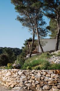 a stone wall and trees in front of a house at Nature House with a wooden porch - Pasika, house Tonka in Pučišća