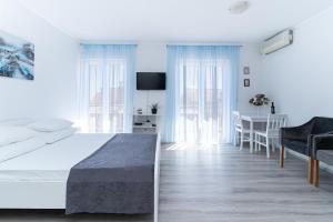 a white bedroom with a bed and a dining room at Benic Apartments in Mlini