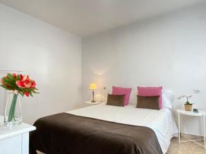 a bedroom with a large bed with pink pillows at Apartamento Padrón Centro P3 by URent in Padrón