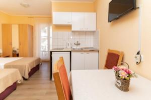a kitchen with two beds and a table with flowers on it at Benic Apartments in Mlini