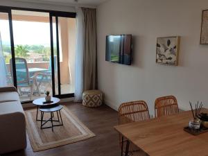 uma sala de estar com um sofá e uma mesa com cadeiras em Chez Adriana Studio Proche Mer avec Piscine em Grimaud