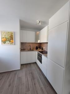 cocina con armarios blancos y suelo de madera en Casa FeLiz, en Tarajalejo
