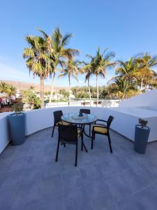 Un patio con mesa y sillas y palmeras. en Casa FeLiz, en Tarajalejo 7 fotos más