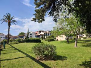 a park with a palm tree and houses at Chez Adriana Studio Proche Mer avec Piscine in Grimaud