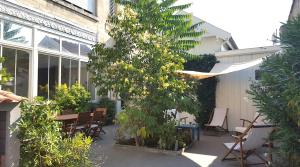 un patio con mesa, sillas y un árbol en B&B La Halte Montaigne en Burdeos