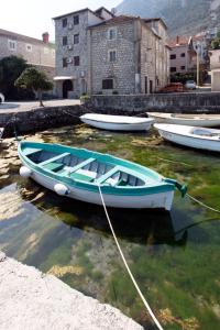 a blue boat is docked in the water at Luxury Seafront flat Perzagno 3 in Prčanj