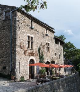 a building with tables and umbrellas in front of it at La Capitelle in Mirmande