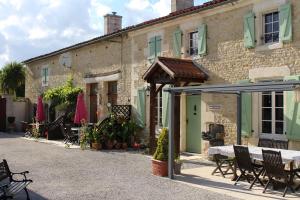 eine Terrasse mit Tisch und Stühlen vor einem Gebäude in der Unterkunft La Pommeraie in Nantillé