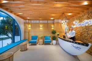 a man standing in a lobby with blue chairs at Santori Hotel And Spa in Danang +182 photos