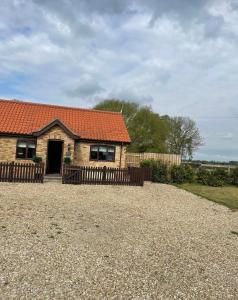 uma casa com um telhado laranja num pátio de cascalho em Oxley Cottage em Alford