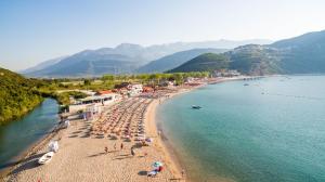 a beach with umbrellas and people on the sand and water at Hotel Palma Jaz Budva in Budva