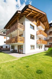 a white building with wooden balconies and a lawn at Residence Ravisa in Selva di Val Gardena