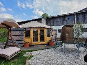 a yurt with a table and chairs in a yard at Fichtel-Jurte - Optional mit Hot Tub in Hohenberg an der Eger