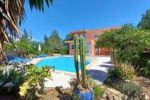 a villa with a swimming pool and cactus at Can reganes in Sant Josep de sa Talaia