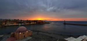 a sunset over the water with a city and the ocean at Amphitrite Hotel in Chania Town