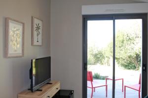 uma sala de estar com uma televisão e uma porta de vidro deslizante em Villa la Dunette & spa em Vaux-sur-Mer