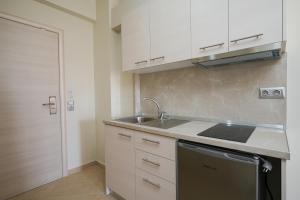 a kitchen with white cabinets and a sink and a dishwasher at Villa MARIA in Nea Vrasna