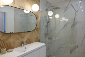 La salle de bains est pourvue d'une douche, d'un lavabo et d'un miroir. dans l'établissement Ostoja Białowieska, à Hajnówka