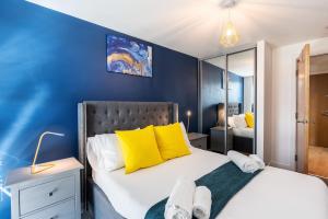 a bedroom with blue walls and a bed with yellow pillows at Lovely 2BR Apt in Sheffield City Centre in Sheffield