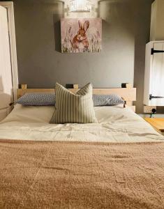 a bedroom with a bed with a picture of a rabbit on the wall at Oxley Cottage in Alford