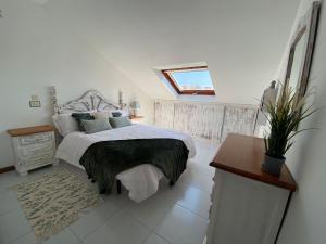 a white bedroom with a bed and a window at Bonito apartamento en la playa in Sanxenxo