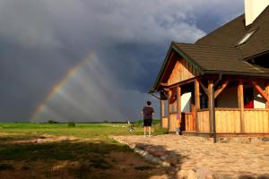 a man standing in front of a barn with a rainbow at Agroturystyka OLZOJA in Posejnele