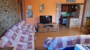 a living room with a couch and a tv at El Corralico del Moncayo in Alcalá de Moncayo