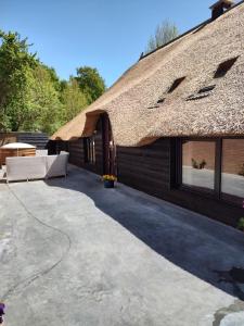 a patio of a house with a thatched roof at Juweeltje van vakantiewoning op prachtig landgoed in Nieuwleusen