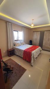 een slaapkamer met een bed met een rode deken bij Chalé de campo em condomínio fechado in Bananeiras