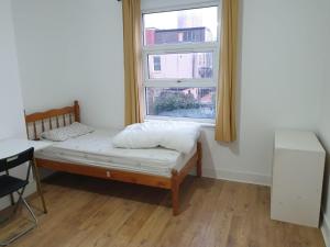 a small bed in a room with a window at Burney Tomar House in Croydon