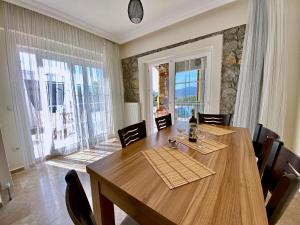 a dining room with a wooden table and a large window at Private Pool - Private 1000m2 Garden, 4 Bedroom - 3 Bathroom - 8 Person, DETACHED Villas, Unlimited WiFi - Free Parking in Fethiye
